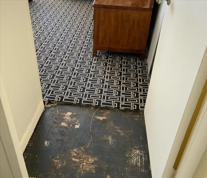 Room entrance with partially removed black and white carpet