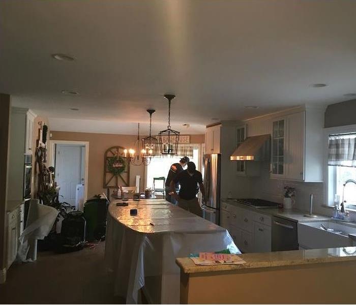 SERVPRO techs in kitchen with plastic-covered island