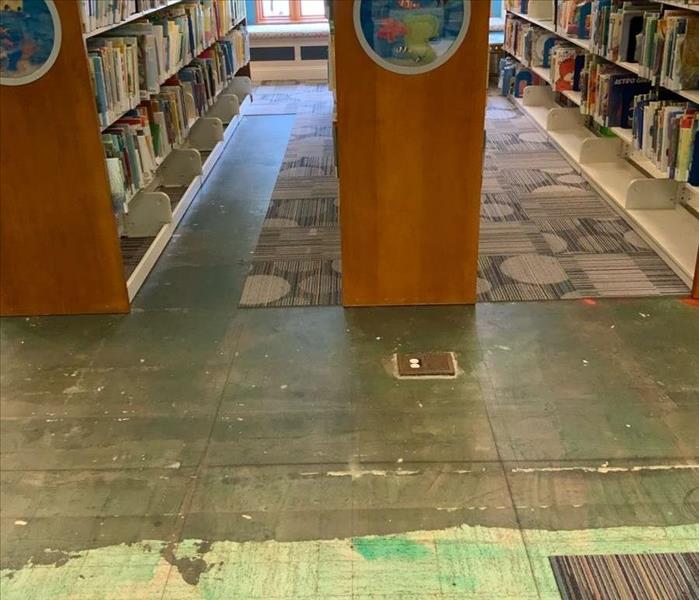 Library with missing portions of the carpet by books on shelves