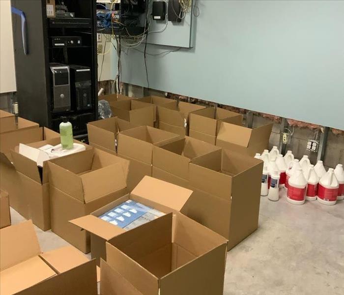 Boxes lined up in a utility room with jugs nearby