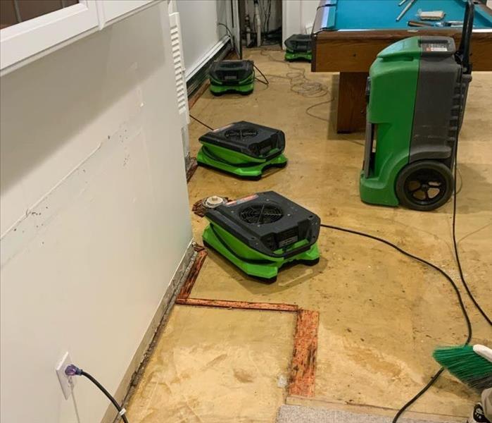 Five stackable air movers and one LGR dehumidifier operating between a basement wall and pool table without baseboards. Some 