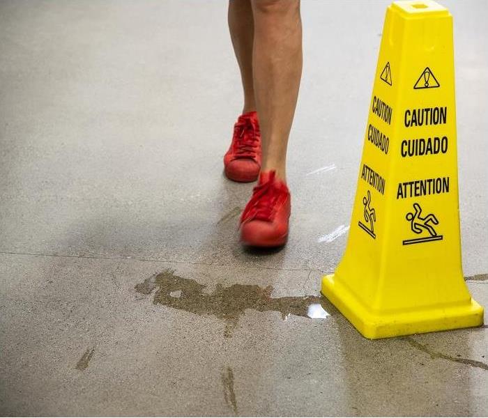 A woman about to step into a puddle of water in a commercial building